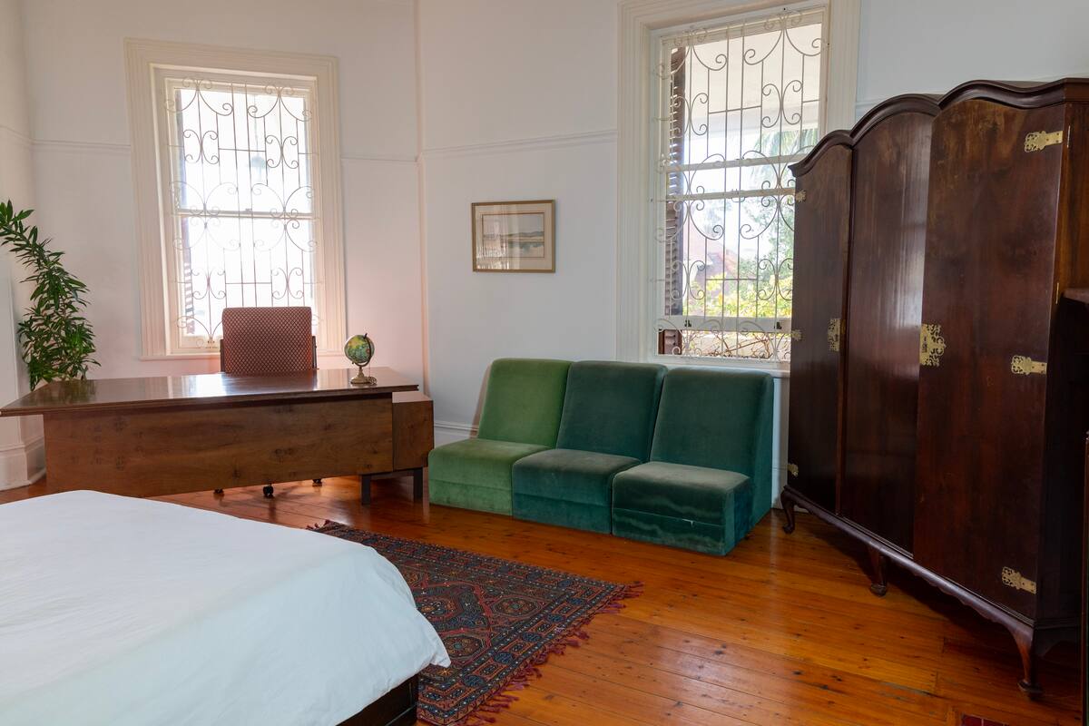 Queen bed and antique wardrobe in the fireplace room at Utopia co-living Cape Town