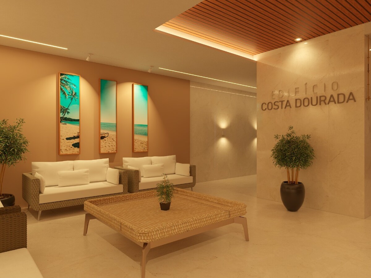 A modern lobby area features two white sofas and a woven coffee table. Wall art depicting serene beach scenes is displayed. Neutral tones and elegant lighting create a calm ambiance. Decorative plants are placed for added greenery, enhancing the welcoming atmosphere.