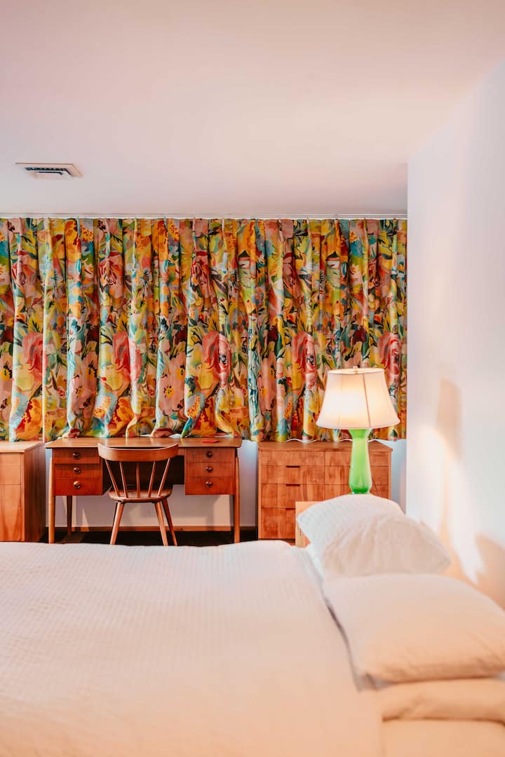 Largest Bedroom + Bath (downstairs)-- vignette of lamp, drapes, and Neutra cabinets.