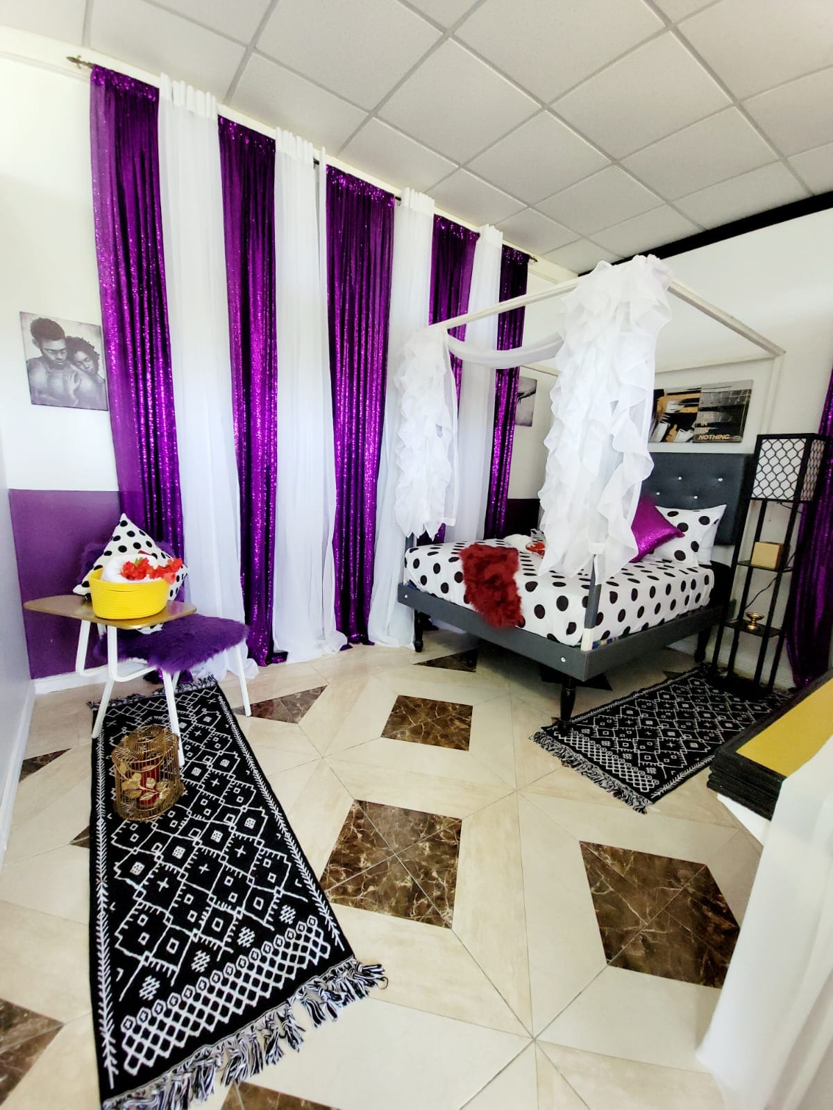 Relax and unwind in our chic and vibrant bedroom, featuring eye-catching purple sequin curtains and stylish decor. The room offers a cozy seating area with a plush chair and a small table, perfect for enjoying a snack or reading a book.