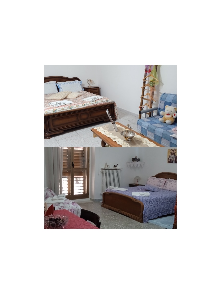 A spacious sleeping area features two wooden beds, adorned with pastel bedding. A decorative blanket is placed on one bed, while a chair and small decorative items are arranged nearby. Light enters through a window with wooden shutters, creating a serene environment.