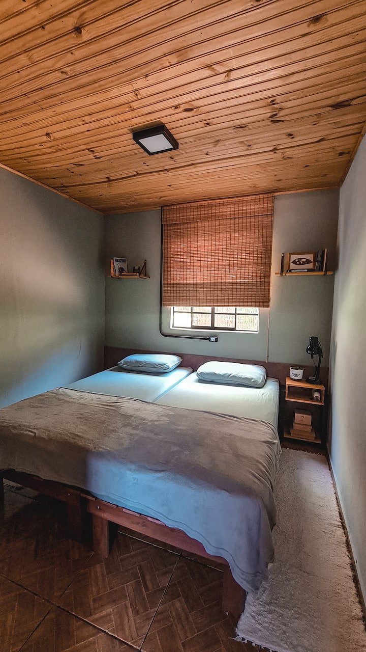 Quarto Araucária, com duas camas de solteiro (que podem ser configuradas como cama de casal), guarda roupa, mesa de cabeceira, prateleiras e espelho de corpo.
