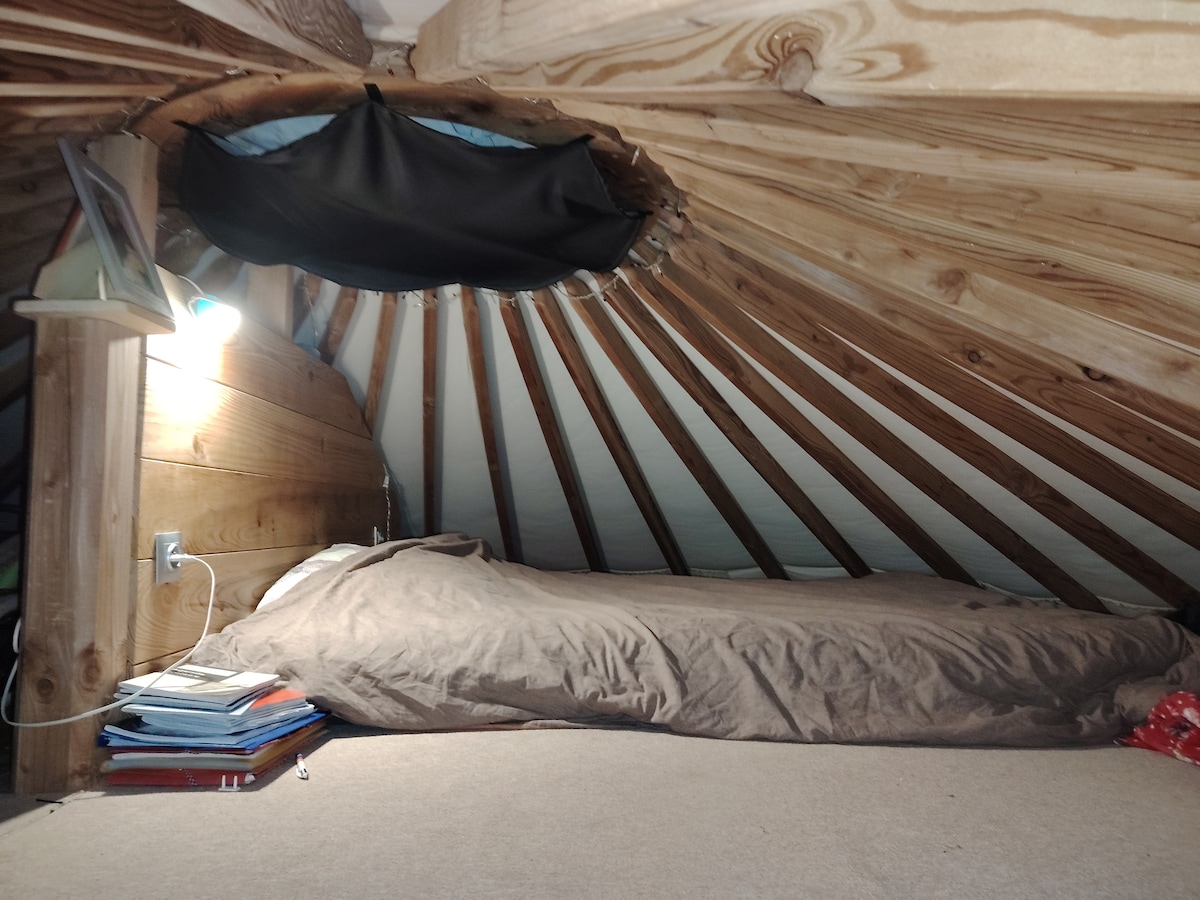 Manželská posteľ sa nachádza v medziposchodí malej jurty. 