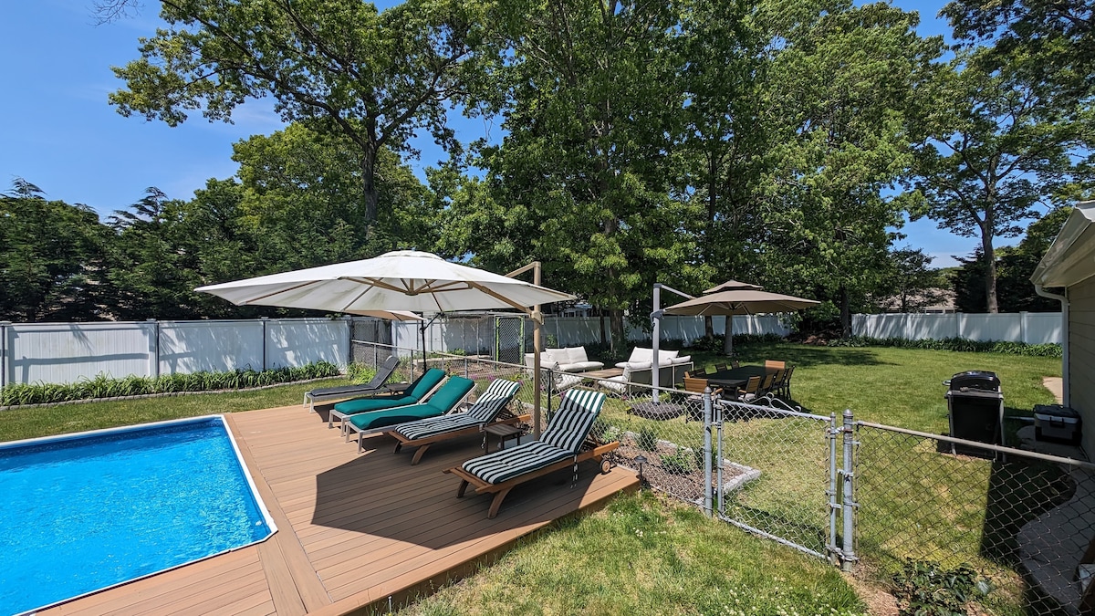 Backyard pool area with lounge chairs and umbrellas