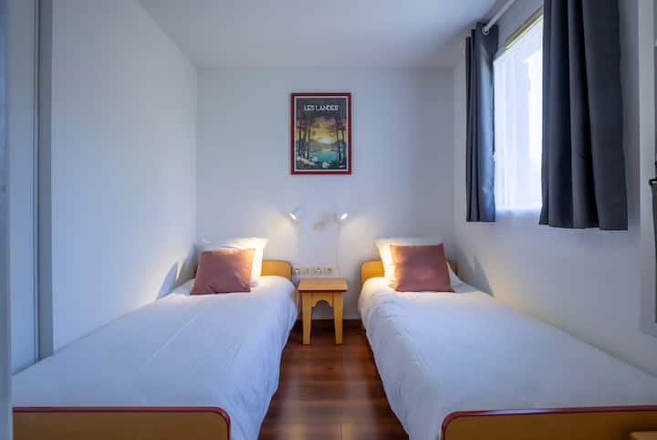 Um quarto projetado para crianças ou amigos, com duas camas de solteiro para que todos tenham seu próprio espaço.