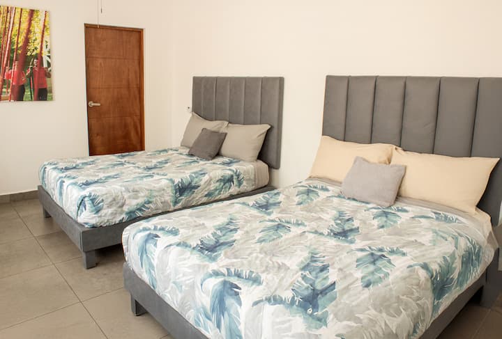 Quarto grande com duas camas de casal, ideal para famílias ou grupos que buscam conforto e espaço para descansar