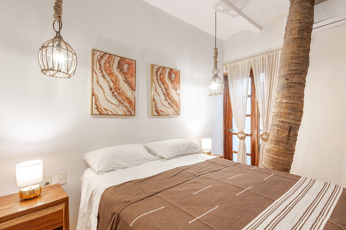 On the walls, paintings with textures reminiscent of shells and waves add an artistic touch, and a faint fragrance of salt and white flowers floats in the air. A living palm tree stands elegantly, like a green sigh of the sea that inhabits the room