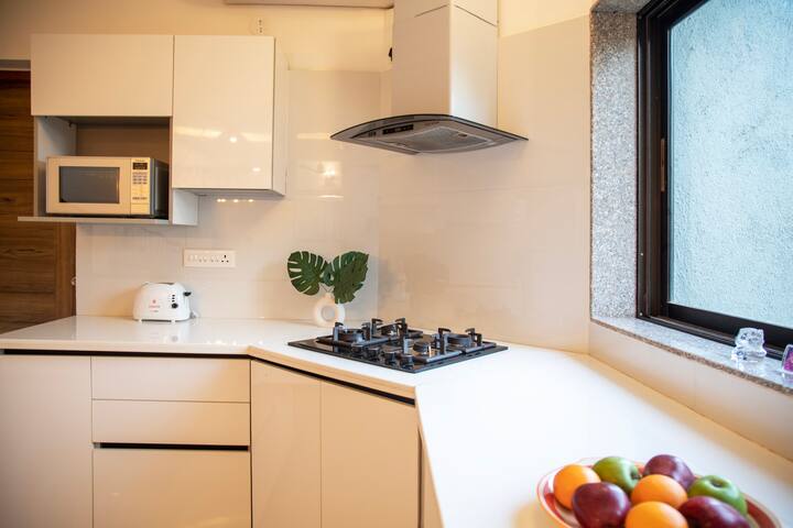 A fully functional kitchen with a stove, gas, kettle, fridge, and microwave, offering plenty of space.