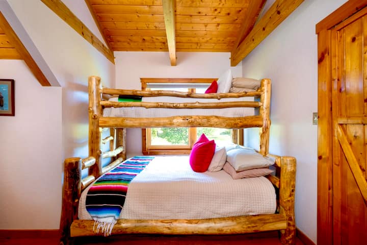 The Bunk Room features a custom timber bunk bed with a queen bed and a twin above. This room has access to Kid's Loft #2. 