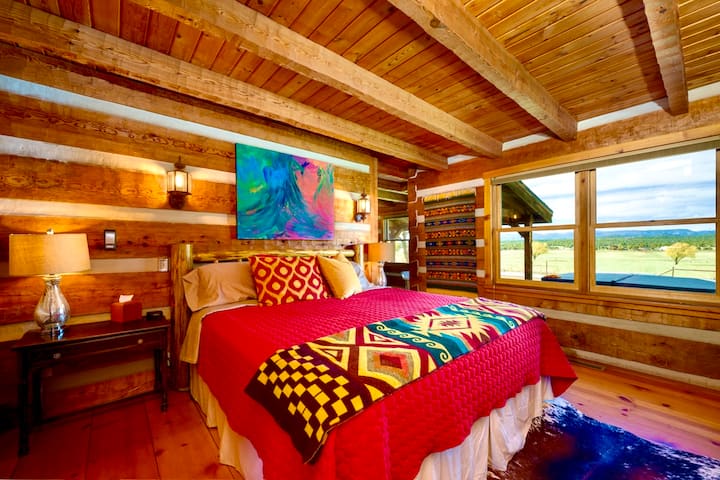The luxurious king bed in the Master Bedroom that features those stunning 180 degree views of the San Juans and surrounding mountains, a beautiful stone  propane fireplace and custom artwork by our daughter and Chance's late mom.