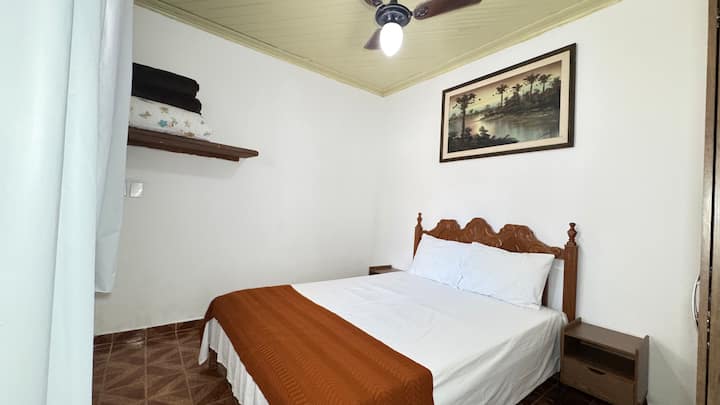 חדר עם מיטה זוגית, מאוורר, מצעים ועיצוב נעים.