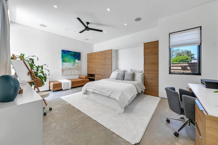 Spálňa na 1. poschodí s nadrozmernou manželskou posteľou Queen, 65-palcovou TV, dennou posteľou a pracovnou stanicou/písacím stolom.