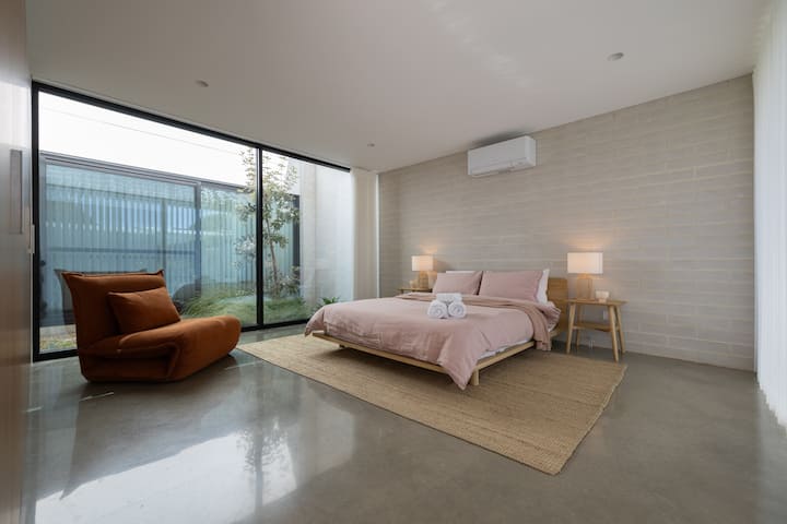 Bedroom 4 is gorgeous! Located on the ground floor, it's spacious, modern, calm and inviting. Boasting floor to ceiling windows on both sides, guests can enjoy views, natural light and access to the internal garden and the private rear courtyard.
