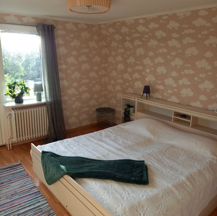 Chambre à l'étage avec lit double et porte du balcon donnant sur le jardin et soleil du soir.