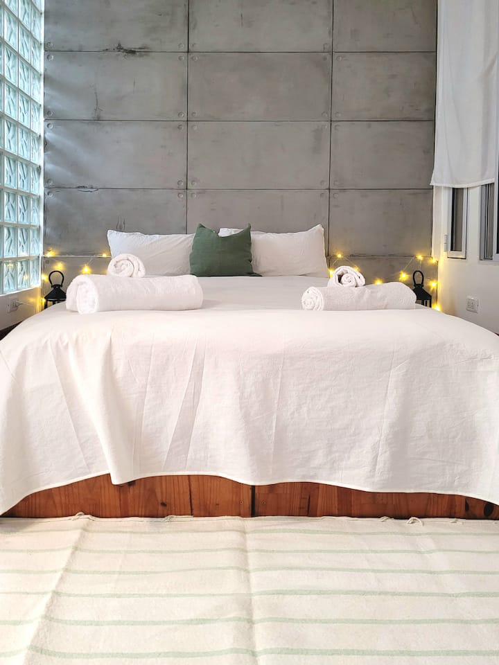 Sovrum med queen bed, stor plakat och eget badrum.