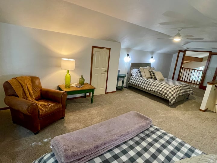Amplio loft en la planta superior, 2 camas tamaño queen y una cómoda silla club de cuero, perfecta para un espacio de lectura privado. Las puertas francesas se abren al pequeño balcón de Julieta con vistas a la sala de estar.