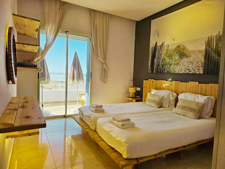 ห้องพักขนาดใหญ่สว่างสดใสพร้อมผ้าปูที่นอนที่สบายและหันหน้าไปทางทะเล