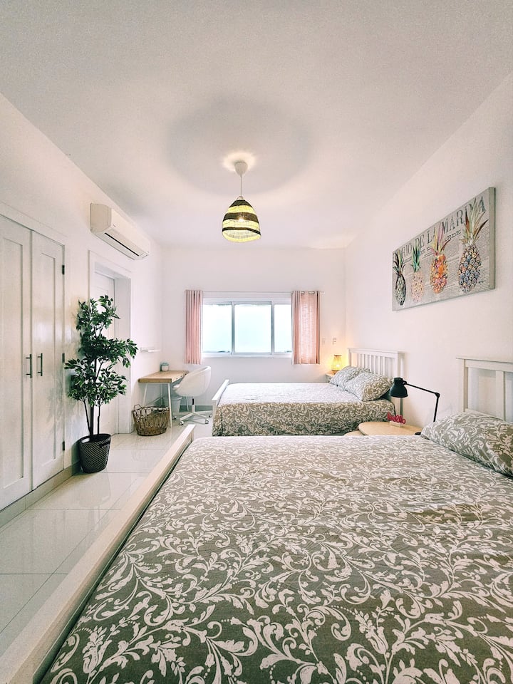 Slaapkamer met 2 queensize bedden, een grote opbergkast en een bureau 