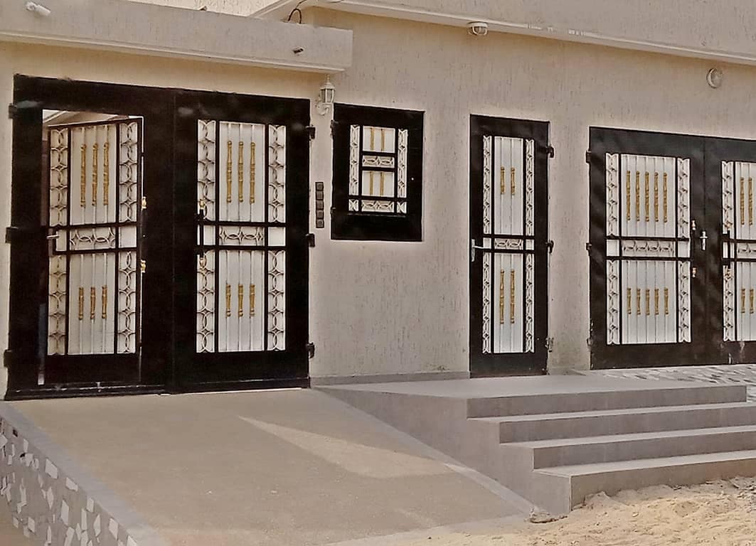 The exterior of the property is highlighted by a series of elegant black doors adorned with decorative gold accents. A set of steps leads to the entrance, providing access to the building's interior. The surrounding area features a paved pathway on a neutral-toned surface.