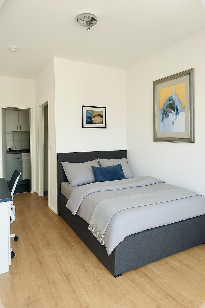 Светлата зона за спане предлага удобно легло за двама души – идеално за спокойни нощи. Модерният интериор и уютната атмосфера осигуряват спокойни часове в апартамента ви.