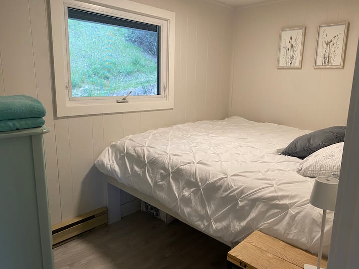 سرير بحجم كبير مع طاولة جانبية لمحطة الشحن وإطلالة على الفناء الخلفي. 