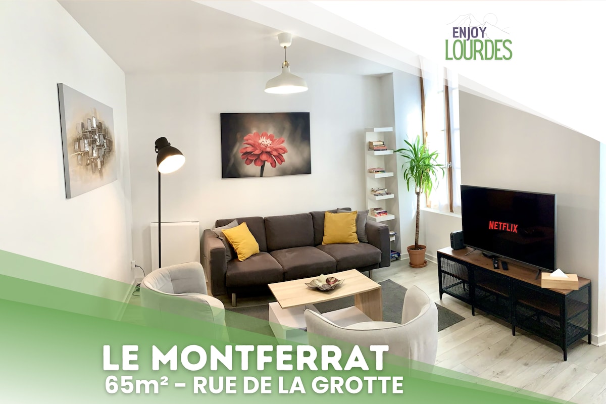 The living area features a comfortable sofa, two armchairs, and a television displaying the Netflix logo. The walls are adorned with artwork, and a coffee table sits at the center. Large windows allow natural light to brighten the room.
