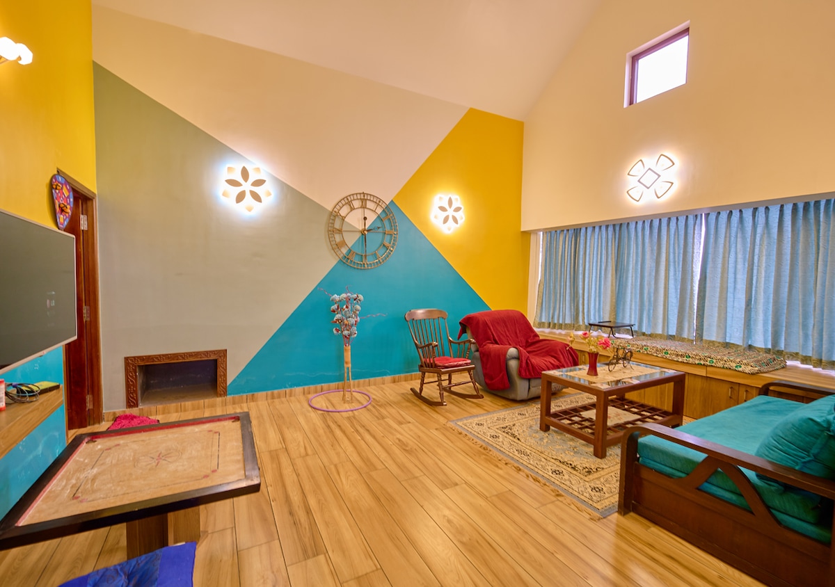 この活気に満ちた居心地の良いリビングルームは、リラックスしてくつろぐのに最適です。 モダンな照明器具を備えたカラフルな幾何学アクセントの壁があり、活気に満ちた芸術的なタッチを加えています。 