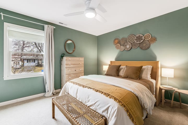Head to bed in our Queen bedroom outfitted with blackout roller shades and curtains. There's two closets with hangers, a clothes organizer, a hamper and a tall dresser. 
