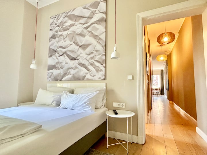 חדר שינה מואר עם מיטה זוגית נעימה, יצירות אמנות גדולות ונוף לכפר. ממול יש חדר אמבטיה עם מקלחת – אידיאלי לנוחות ופרטיות. מושלם כדי להירגע אחרי יום עמוס.