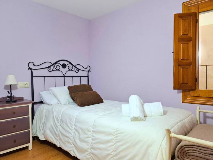 ห้องเล่นเกมถูกเปลี่ยนเป็นห้องนอนเดี่ยวพร้อมเตียงขนาด 90 ซม. และหัวเตียงเหล็กดัด การตกแต่งในโทนสีอ่อนโต๊ะพร้อมโคมไฟและหน้าต่างไม้ที่ให้แสงธรรมชาติ เหมาะสำหรับรองรับความต้องการที่แตกต่างกัน