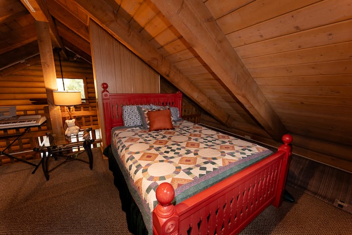 Third-floor loft featuring a queen bed, dedicated desk workspaces, closet, and a TV with Roku and Wii for entertainment at the Forest Lodge near Silverwood Theme Park.