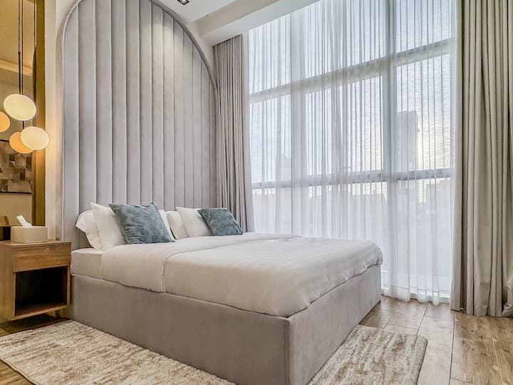 Dhomë gjumi me krevat dopio "king-size" dhe dritare nga dyshemeja në tavan me pamje nga rruga King Fahad