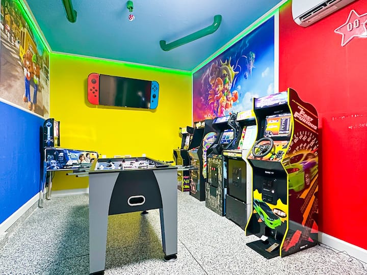 Გააუმჯობესეთ თქვენი გართობა ამ Super Mario არკადულ ლაუნჯში! Მწვანე და წითელი კედლები წარმოაჩენს გიგანტურ მარიოს მოხატულ და ნეონის ვარსკვლავებით განათებულ განათებას, ხოლო ვინტაჟური კარადები-Street Fighter II, Pac-Man, Donkey Kong და ფოსბოლის მაგიდა უწყვეტი კლასიკური სათამაშო მოქმედებებით