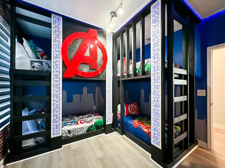 Მოირგეთ შურისმაძიებლების ამ ინდივიდუალურ ორსართულიან ოთახში! Ოთხი გამძლე, ქალაქის პეიზაჟის ჩარჩოში ჩასმული ორსართულიანი საწოლი მზადაა თქვენი გმირების გუნდისთვის, თითოეული მათგანი აღჭურვილია კაპიტანი ამერიკაში, ჰალკში, თორსა და რკინის კაცის თეთრეულში. Გამუქებული ლურჯი კედლები, შუქდიოდური აქცენტები და საკულტო „A“ ლოგო  