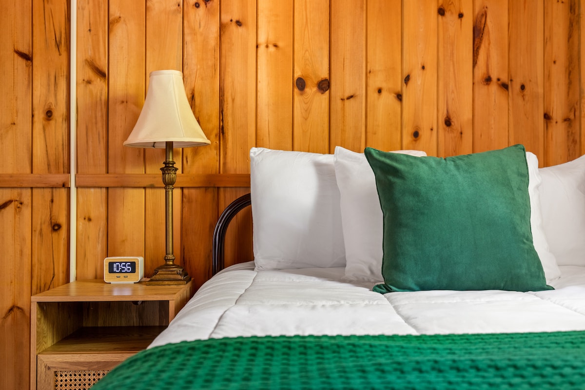 Удобна и привлечна, оваа спална соба има удобен полн кревет, плакар и ноќно шкафче со порти за полнење. Со топла дрвена ламперија и мека кадифена постелнина, овој шармантен простор нуди мирно прибежиште далеку од вревата на денот.