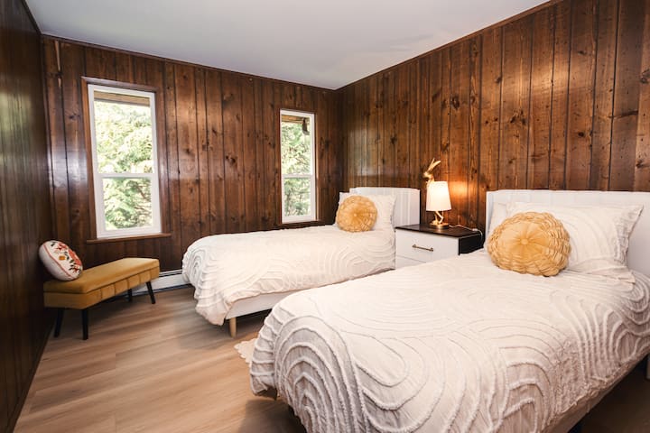 Inclus : inclus dans le prix de la location. Chambre à deux lits chaleureuse et accueillante avec de la literie blanche confortable, des murs en lambris et une lampe en forme de lapin pour ajouter du charme.