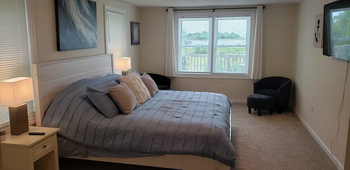 Waterway and island views - First bedroom with king size bed, large screen smart TV, walk-in closet, sitting area, alarm clock, bed side tables, dresser, mirror, and private bathroom.