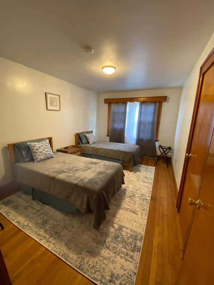 Dormitorio #2 con 2 camas individuales, unidad de ventana de aire acondicionado y un armario.