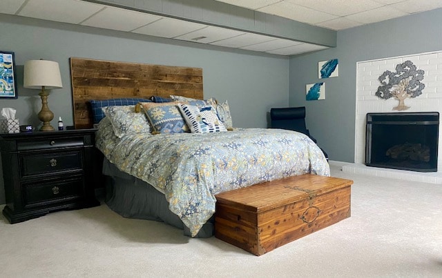 A spacious bedroom features a comfortable bed adorned with patterned bedding. A rustic wooden headboard complements the decor, while a wooden trunk sits at the foot of the bed. A cozy fireplace and a lamp are visible, adding to the room's inviting ambiance.