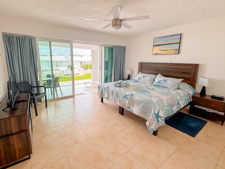 king size bedroom with private covered terrace and garden in front, partial ocean view