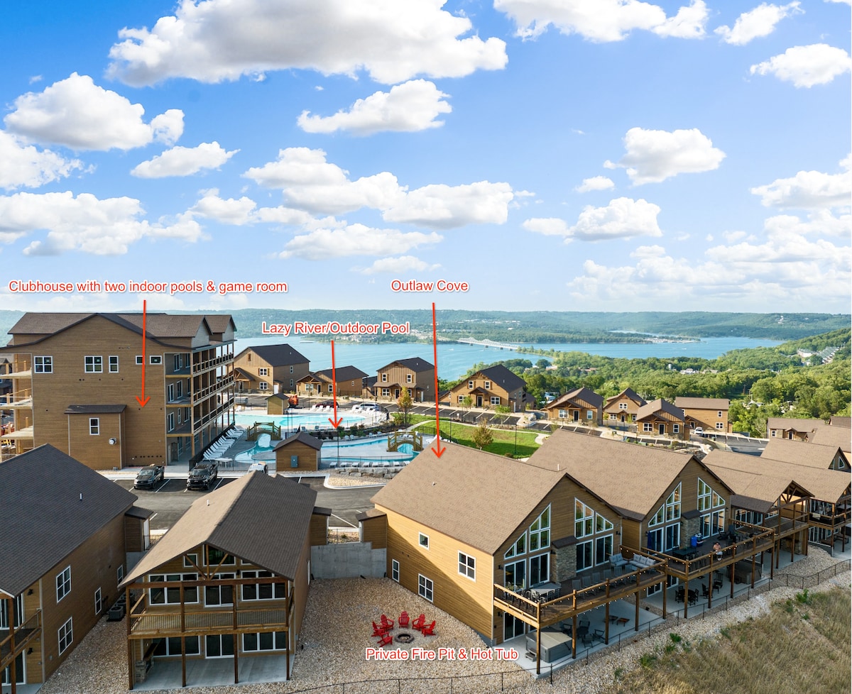 An aerial view captures the Outlaw Cove lodge and its surroundings, displaying a community clubhouse with indoor pools and a game room. The expansive outdoor lazy river pool and stunning lake views are prominent, highlighting the scenic location within Wilderness Mountain.