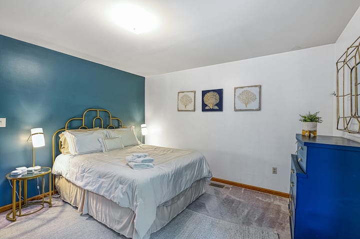 First-floor master bedroom with queen bed, ocean-inspired decor, and peaceful tones for restful nights. Includes an attached full bathroom for added comfort.