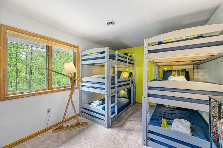 Second-floor bunk room with 6 beds, playful colors, and forest views — perfect for kids or large groups.