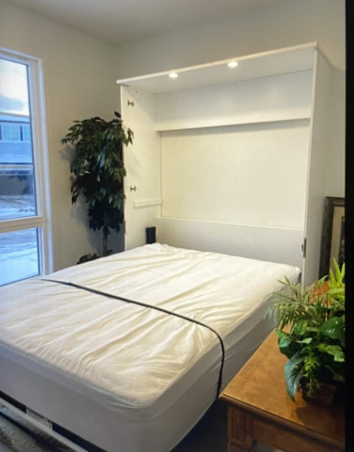 El dormitorio del piso principal es flexible con una cama murphy tamaño queen (colchón de calidad hotelera) que se puede plegar para que la habitación se convierta en una oficina. El escritorio se encuentra a lo largo de la pared lateral.