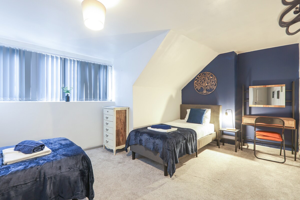 卧室配有两张单人床，每张均配备干净的床上用品和毛巾。 带桌椅的书桌区域完善了工作或休闲空间。


