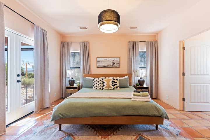 Relax in a stylish Southwestern bedroom featuring terracotta floors, earthy tones, cozy lighting, and a plush king bed—your desert retreat awaits!
