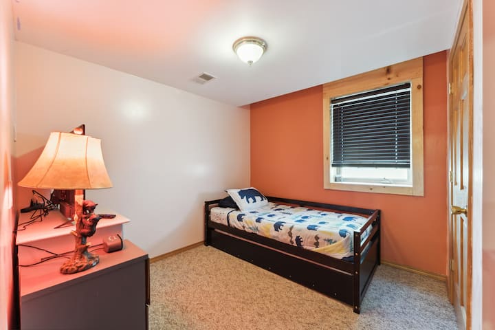 Basement bedroom with one trundle (two twin beds), dresser, Roku TV, USB charging ports, alarm clock, hangers, closet, and many games and toys. 