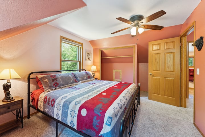 Upstairs bedroom with a king bed, work desk, Roku TV, USB charging ports on lights, dresser, closet with hangers