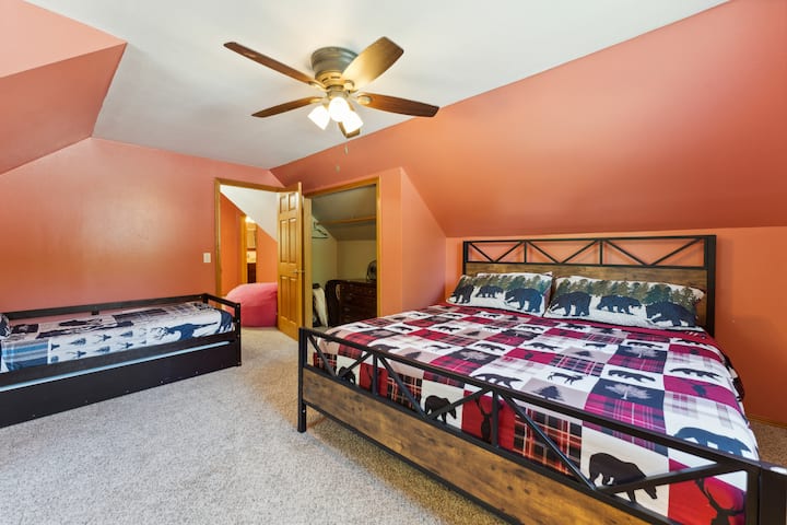 Upstairs bedroom with one king bed, one trundle (two twins), dresser, Roku TV, USB charging ports, hangers and closet, pack n' play, coloring books, and baby toys