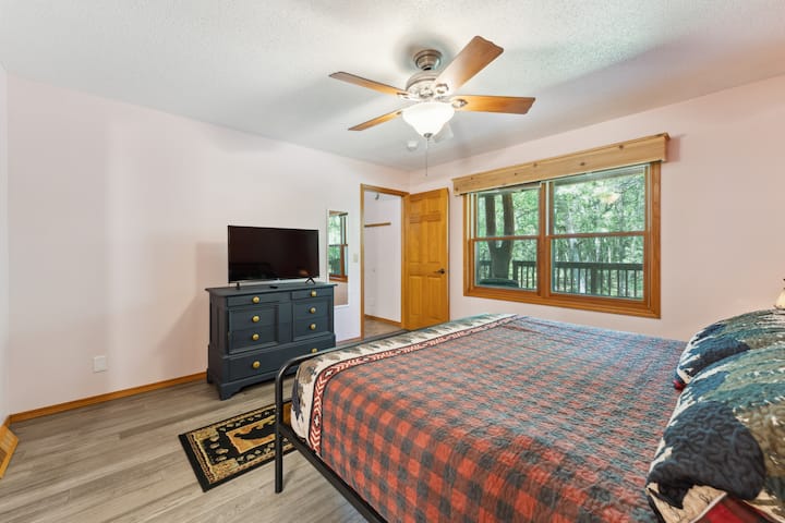 Master Suite Main Level Bedroom with a king bed, Roku TV, USB charging ports on lights, dresser, closet with hangers, master bathroom connected to the bedroom with tub/shower, hairdryer, and iron/ironing board. 